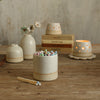 White match pot with pastel matches in front of white vases, lit tealights and old books