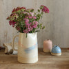 Paintbrush Pitcher Jug filled with wildflowers next to a small pink vase and a mini blue vase