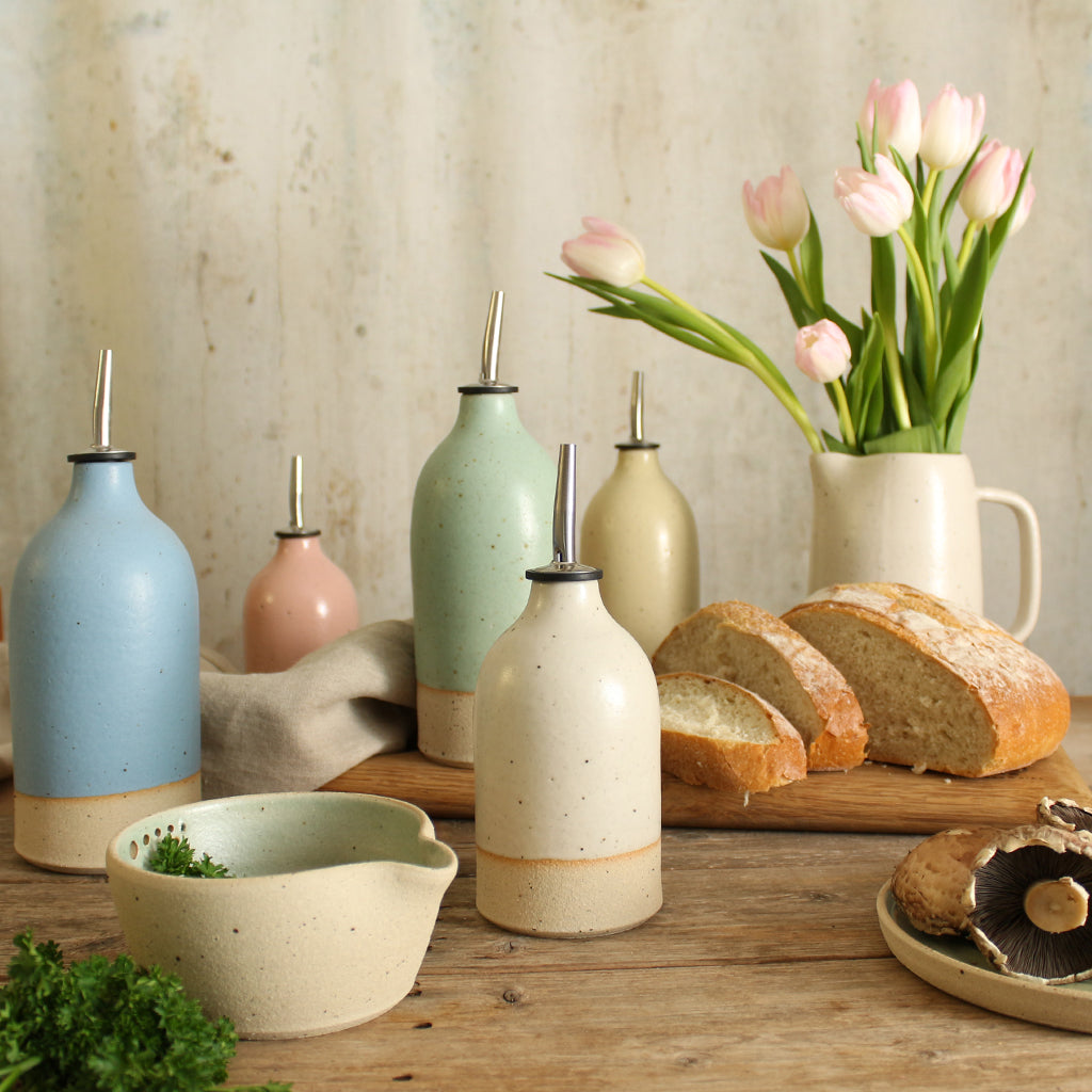 kitchen table display with handmade ceramic oil pourers in 5 pastel shades, tulips in a ceramic jug