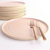 Pale Pink dinner plate with copper cutlery next to stack of plates