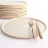 Off-White dinner plate with copper cutlery next to stack of plates