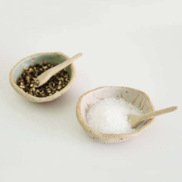 two mini bowls, one with salt and one with pepper and mini spoons