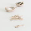 Close up of mini handmade clay spoon in front of pile of mini spoons