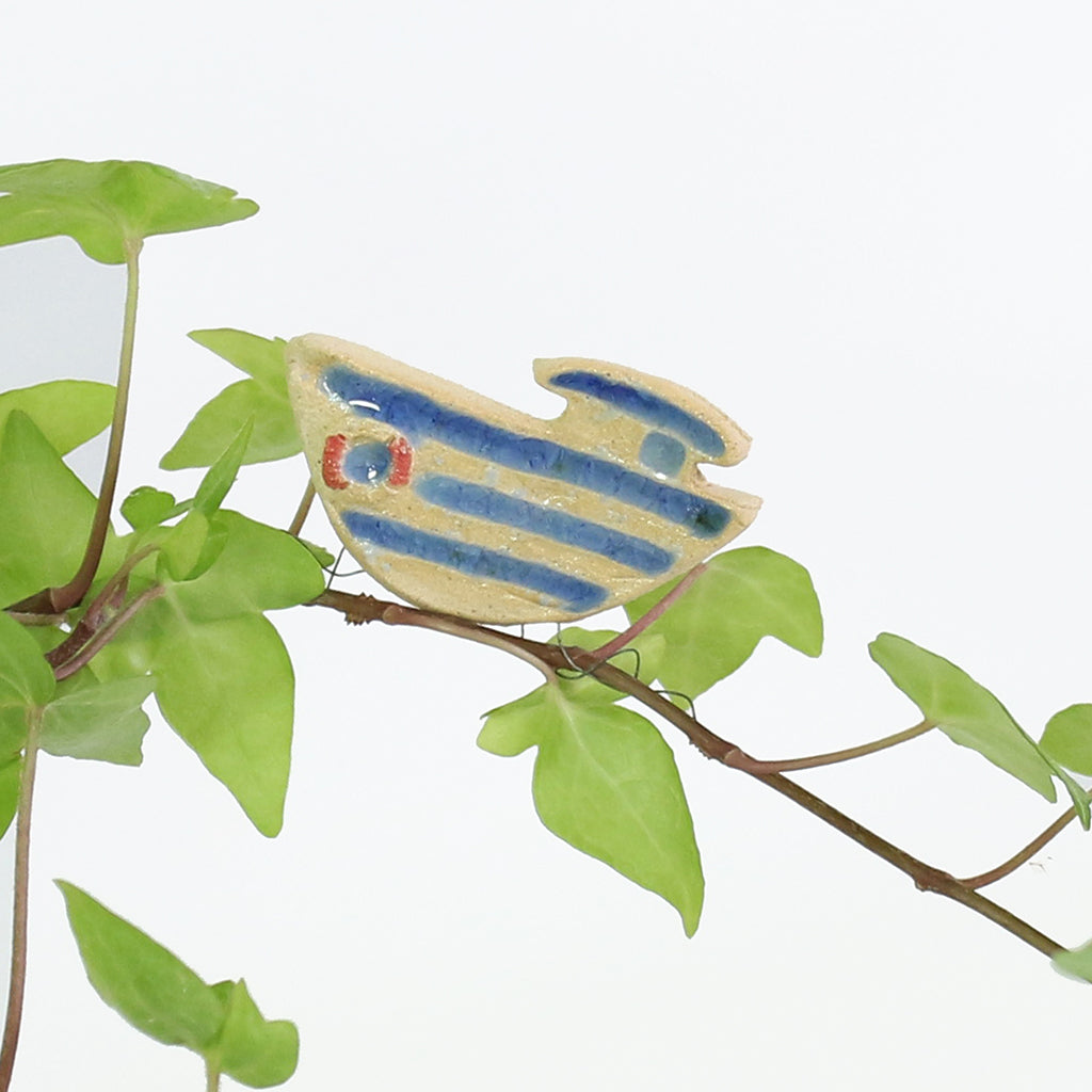 small ceramic and glass boat plant decoration, with thin wire wrapped around house plant stem