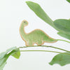 small ceramic and glass emerald green brontosaurus dinosaur plant decoration, with thin wire wrapped around house plant stem