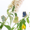 three small ceramic and glass butterfly plant decorations on plant stems