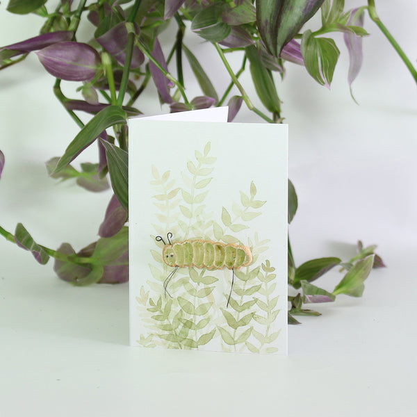 small ceramic and glass green caterpillar plant decoration on gift card with watercolour leaves