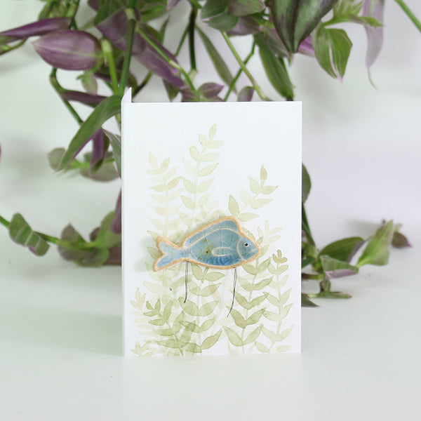 small ceramic and glass sapphire blue fish plant decoration, on gift card with watercolour leaves