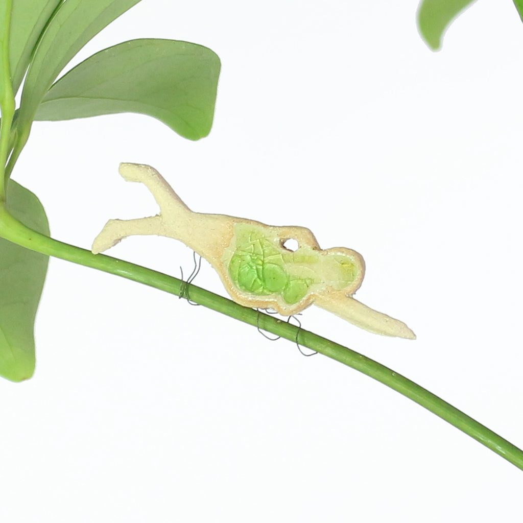 small ceramic and glass swimmer with emerald green cap and costume, with thin wire wrapped around house plant stem