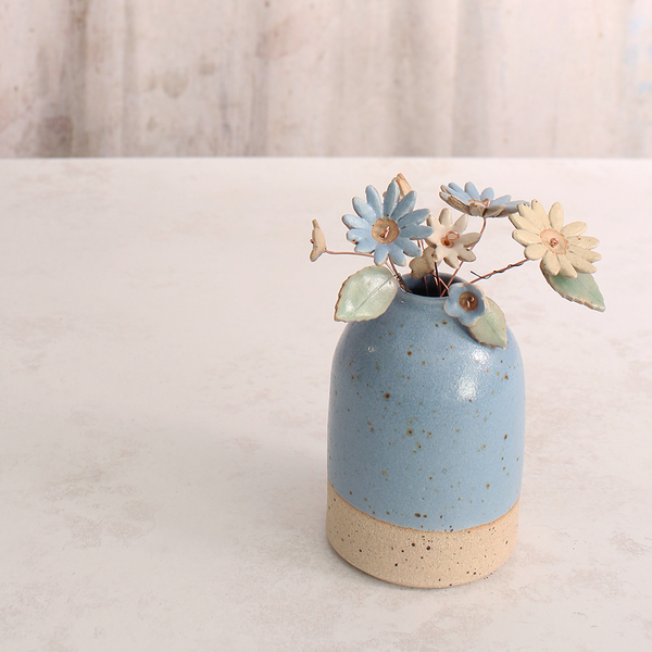 Handcrafted ceramic flower bouquet in a vase, featuring delicate blue and white wildflowers with green leaves, arranged with copper wire stems — perfect for rustic home decor.