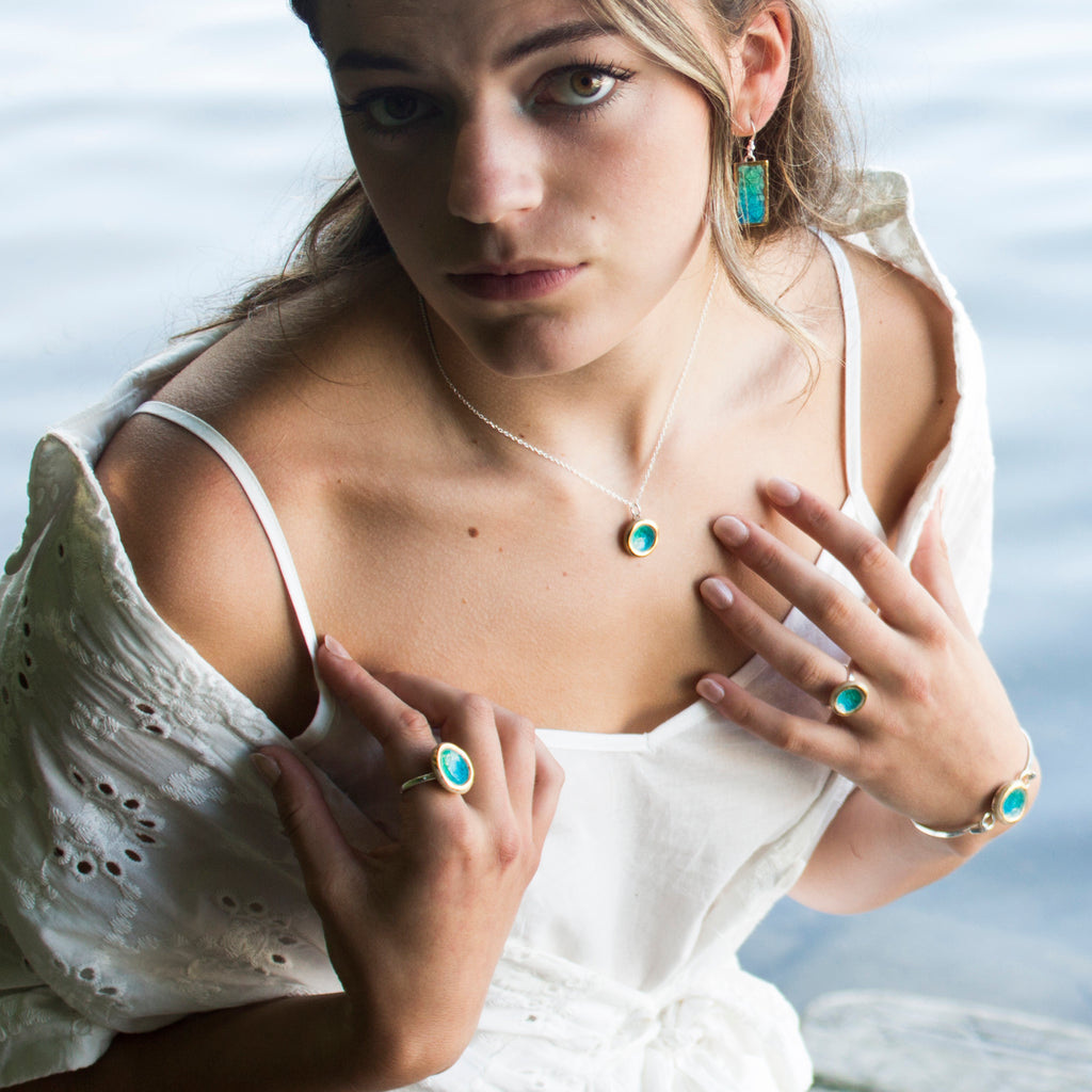 model wearing emerald turquoise glass and ceramic round pendant, rings, bangle all with gold detailing - Habulous