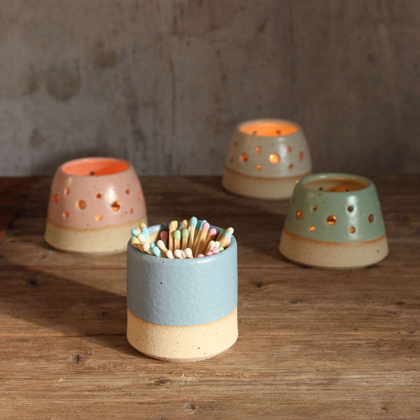 blue match pot with pastel matches in front of lit tealights