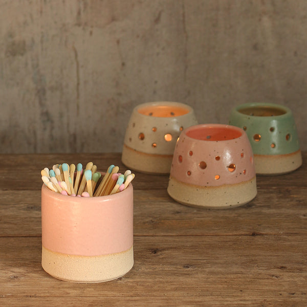 Pink match pot with pastel matches in front of lit tealights