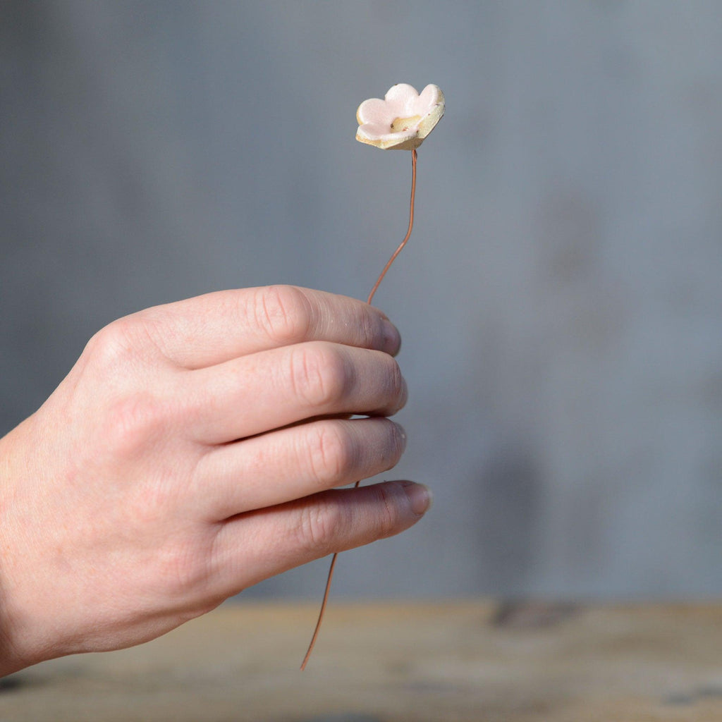 Hand holding pink ceramic flower bud stem