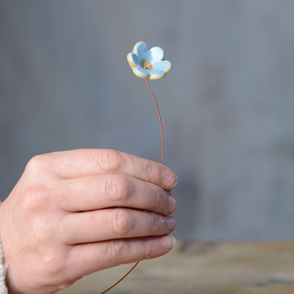 Hand holding blue ceramic flower bud stem