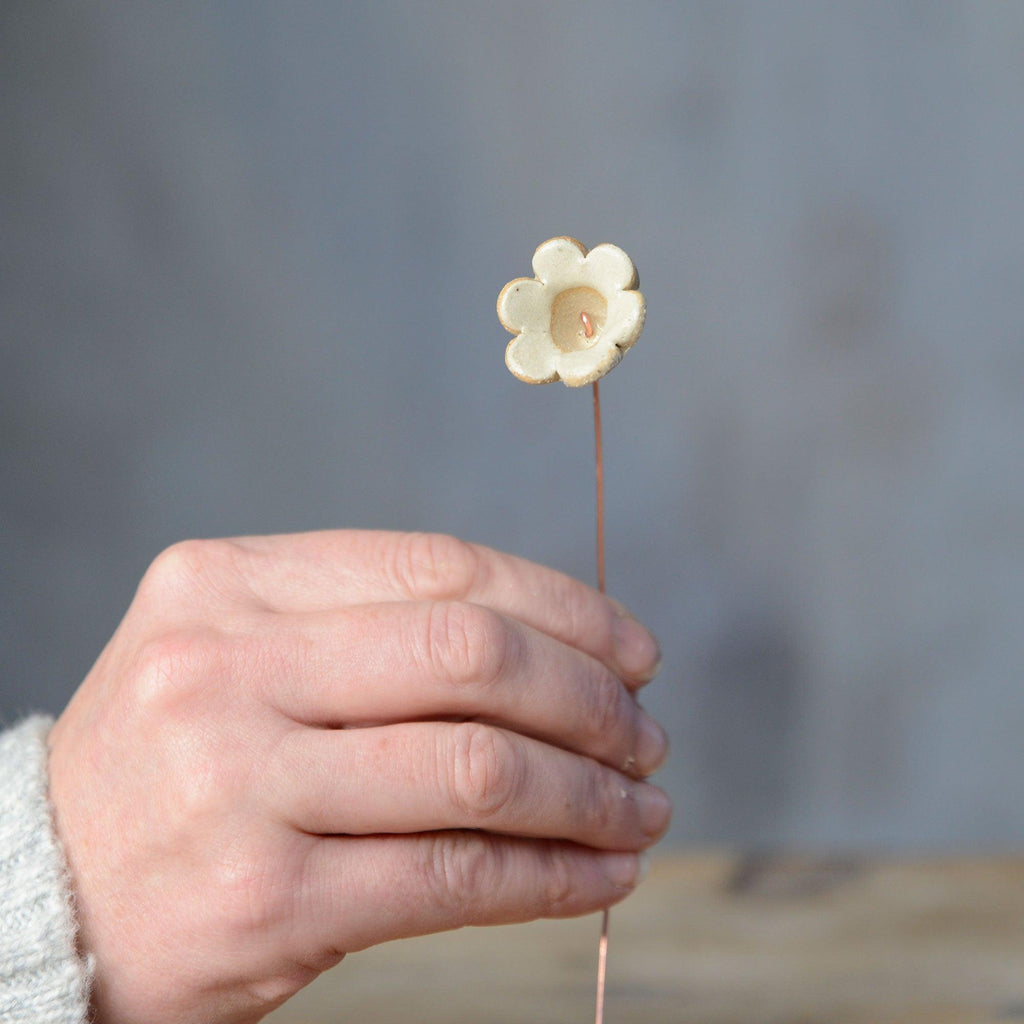 Hand holding yellow ceramic flower bud stem